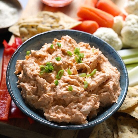 A crockpot buffalo chicken dip with carrots, celery and crackers.