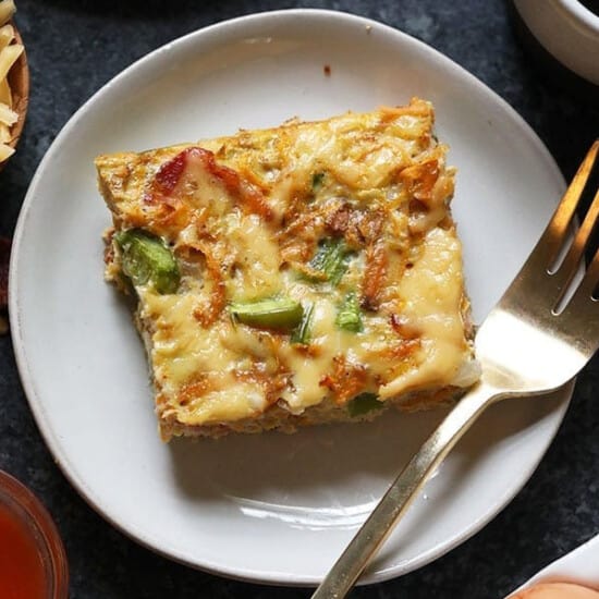 A plate with a piece of quiche and a fork.