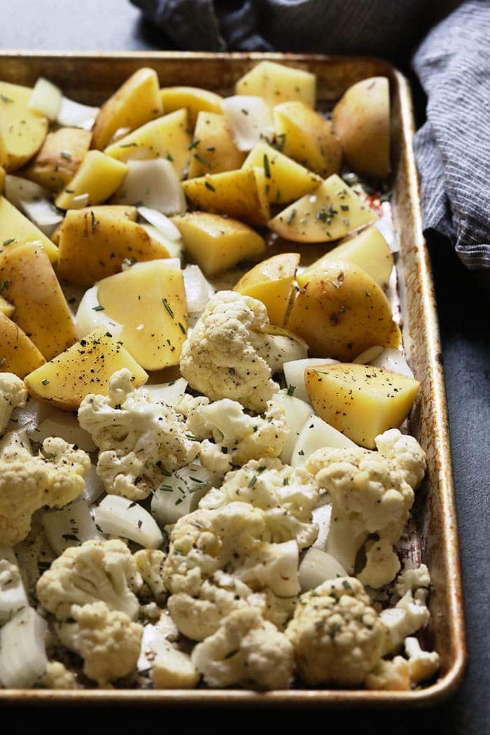 seasoned potatoes and cauliflower on a baking sheet