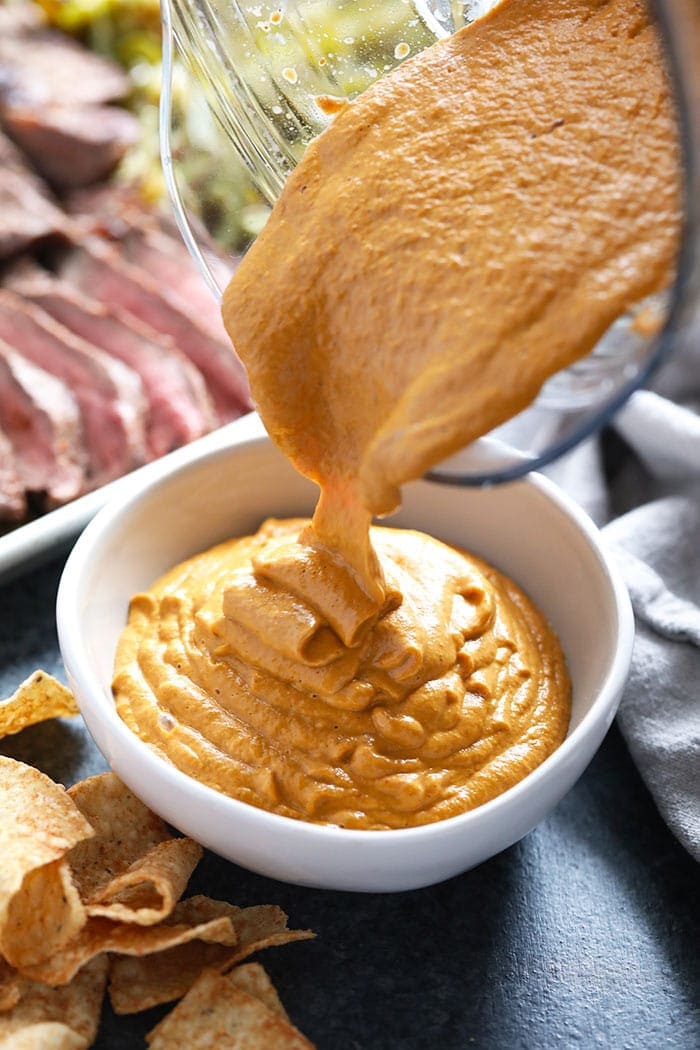 Vegan queso being poured in a bowl.