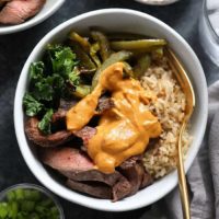 A bowl featuring Philly cheese steak alongside green beans and rice.