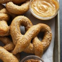 A tray of soft pretzels with peanut butter and mustard.