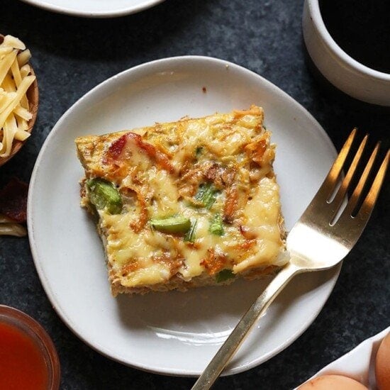 a healthy breakfast casserole on a plate next to a cup of coffee.