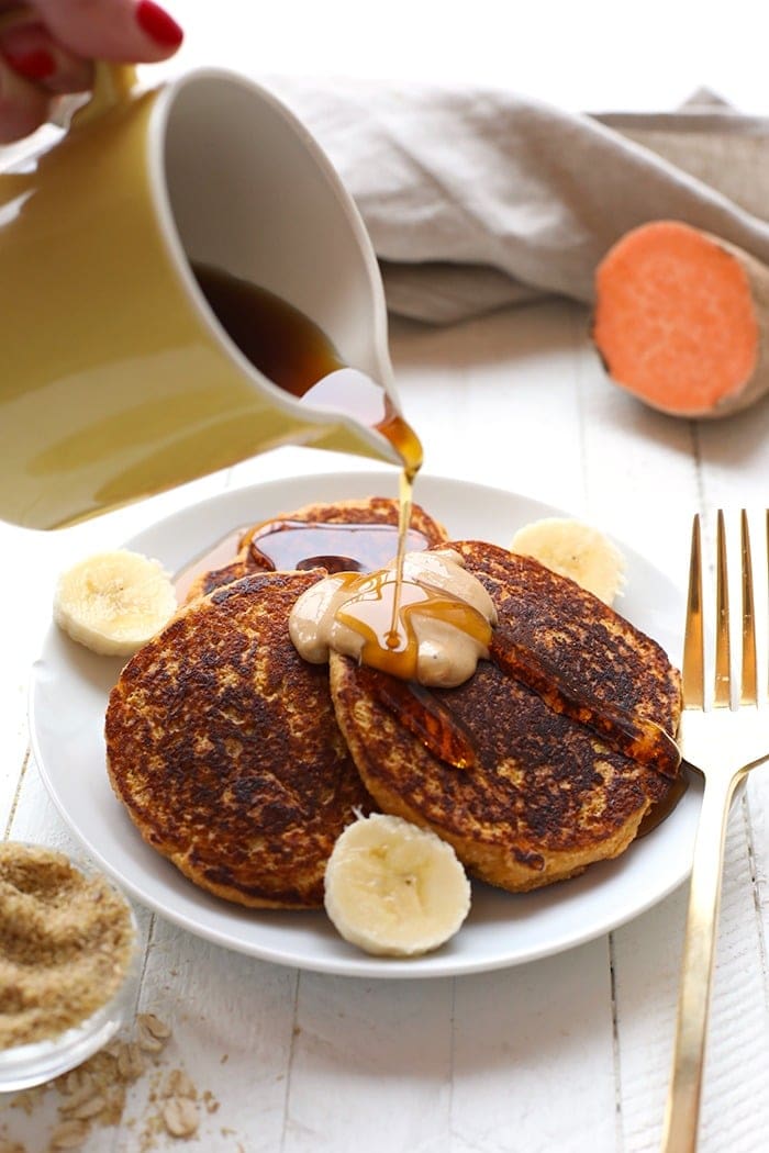 Start your morning out right with these Sweet Potato Pancakes! This healthy pancake recipe is made with 100% oat flour and sweet potato puree and are packed with vitamin A and fiber so you'll feel energized all day long. Pouring maple syrup on sweet potato pancakes