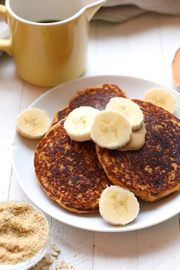Start your morning out right with these Sweet Potato Pancakes! This healthy pancake recipe is made with 100% oat flour and sweet potato puree and are packed with vitamin A and fiber so you'll feel energized all day long. Sweet potato pancakes on a plate