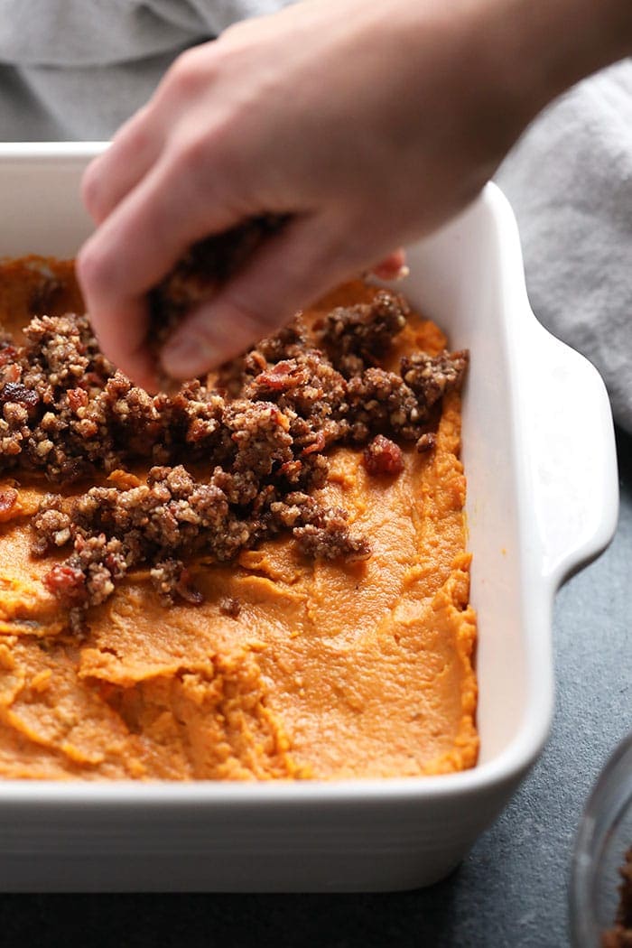 crumble topping being sprinkled on the top of pureed sweet potatoes