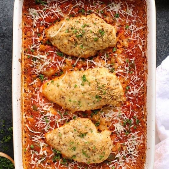 Chicken breasts baked with parmesan cheese in a casserole dish.