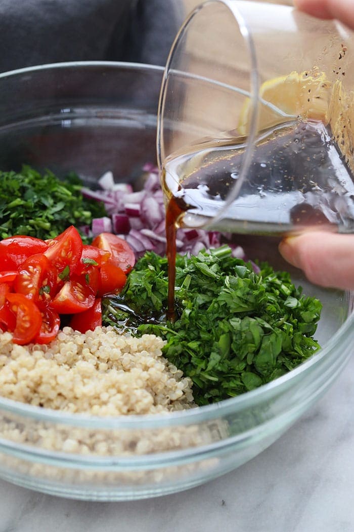 Dressing being poured over the quinoa tabouli salad. 