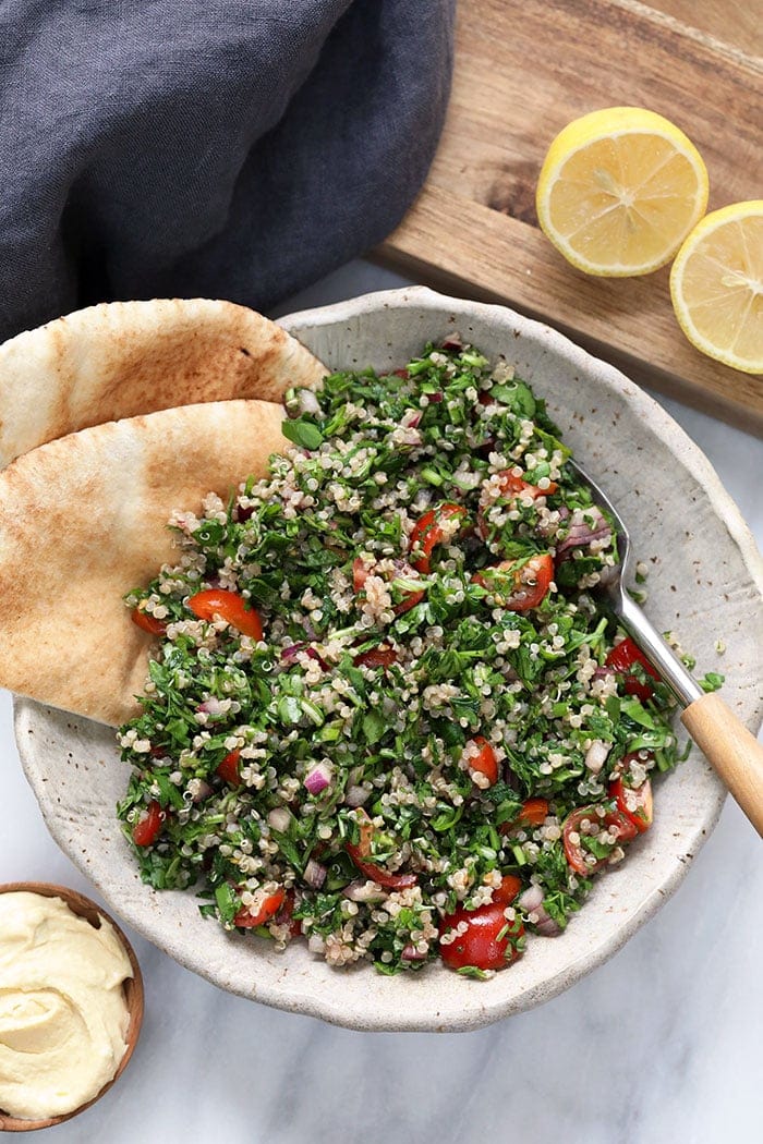 A bowl of quinoa tabouli with a spoon in it. 