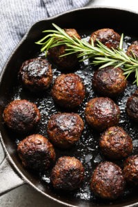 Easy meatball recipe cooked in a skillet with a rosemary sprig.