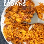 Sweet potato hash browns cooked in a pan with a fork.