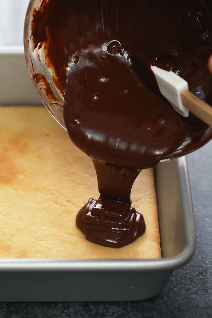 pouring chocolate over the top of almond shortbread crust