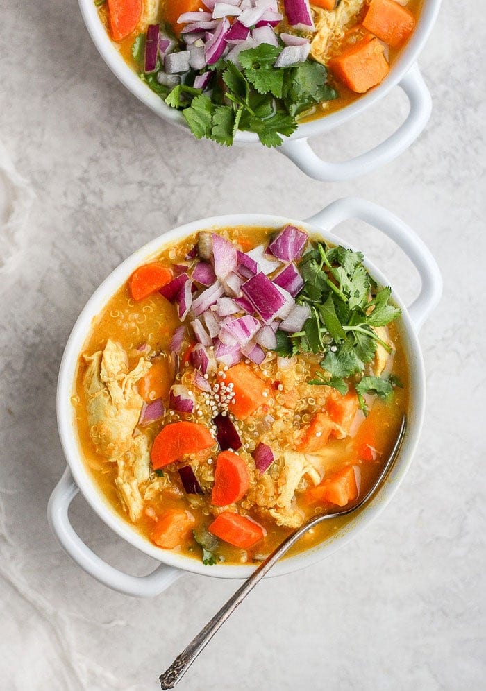 Two bowls of curry chicken soup with carrots and onions.