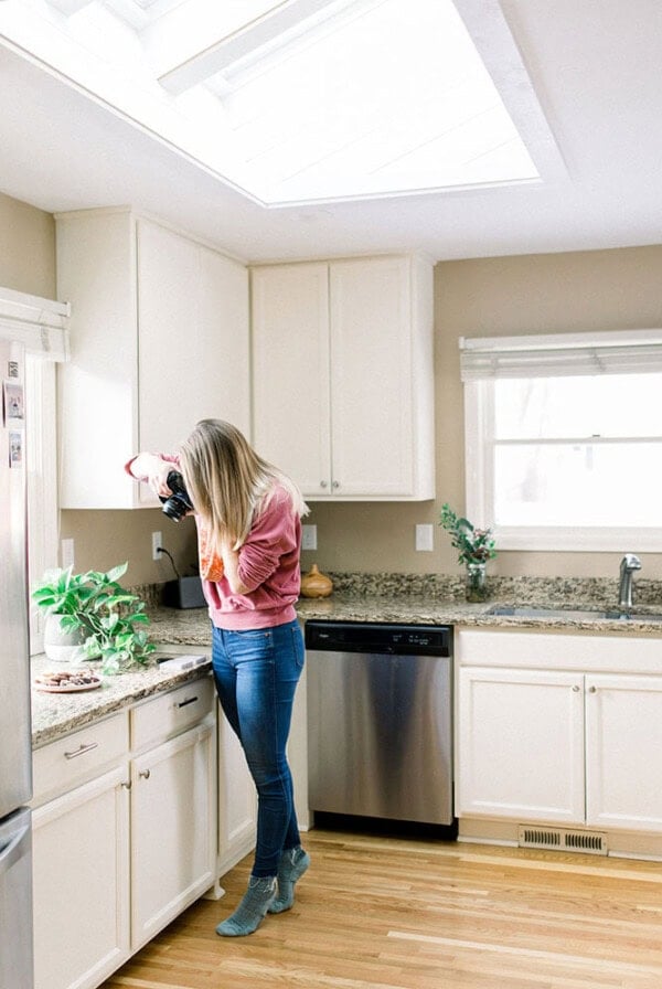 A woman stands in a kitchen with stunning skylights.