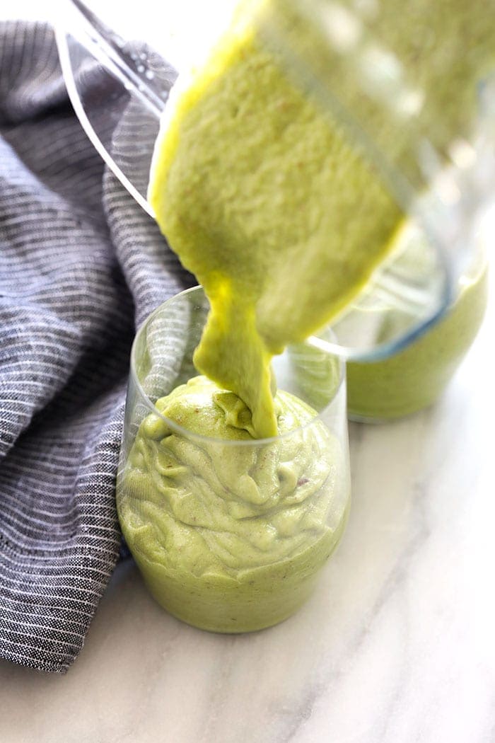 Pouring a green smoothie into a glass