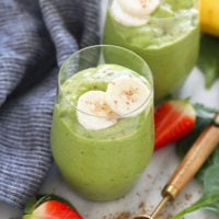 Two glasses of green smoothie with bananas and strawberries.