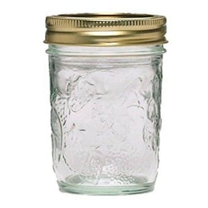 A mason jar with a gold lid containing Avocado Cilantro Lime Dressing on a white background.
