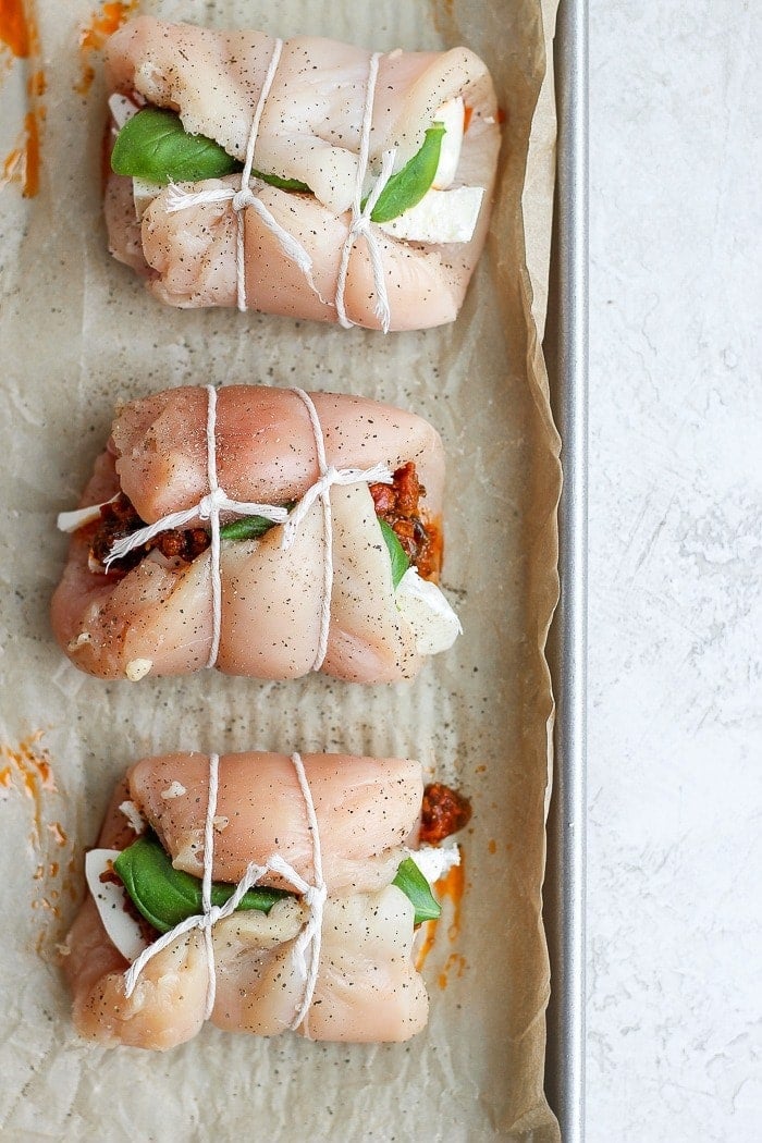 Caprese stuffed chicken breast rolled up on a baking tray