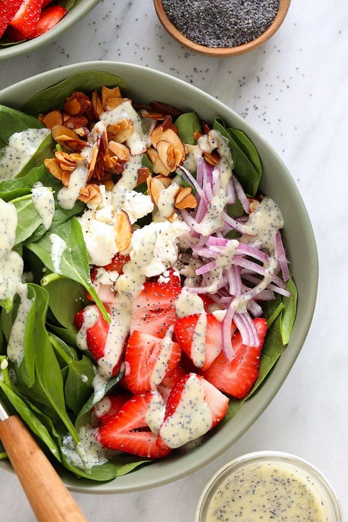 Strawberry spinach salad in a bowl topped with poppyseed dressing.