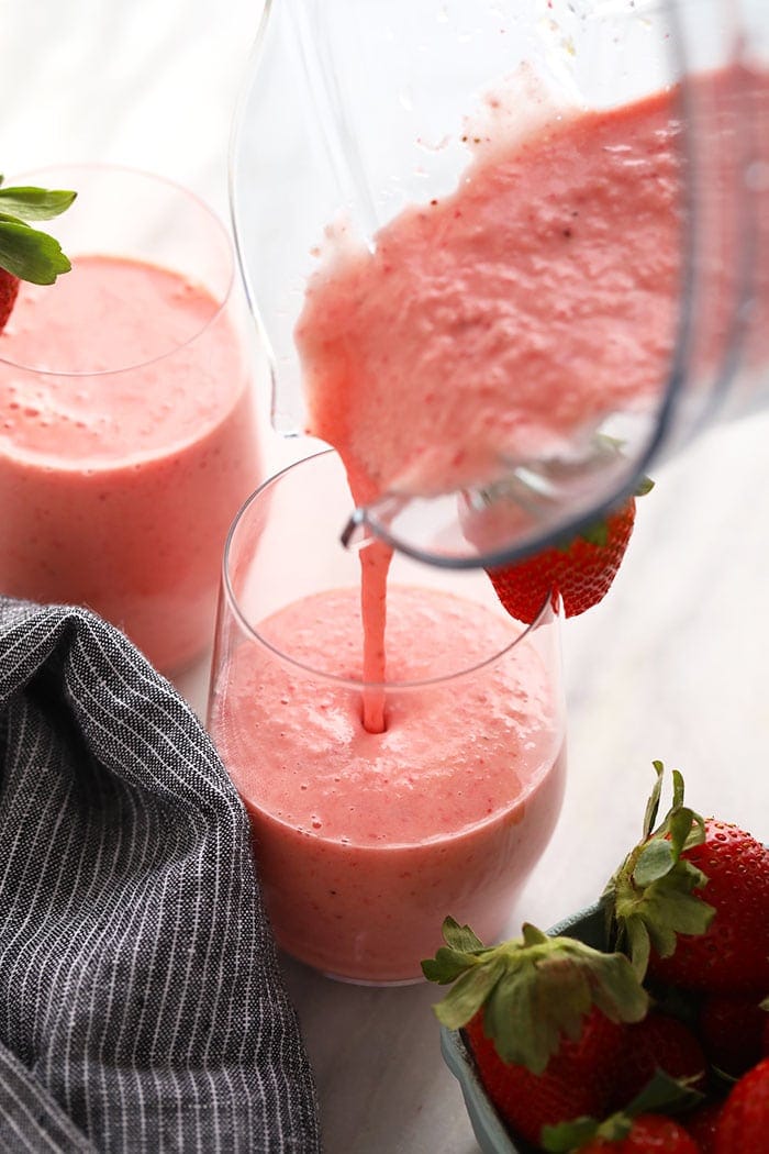 Strawberry smoothie being poured into a glass.