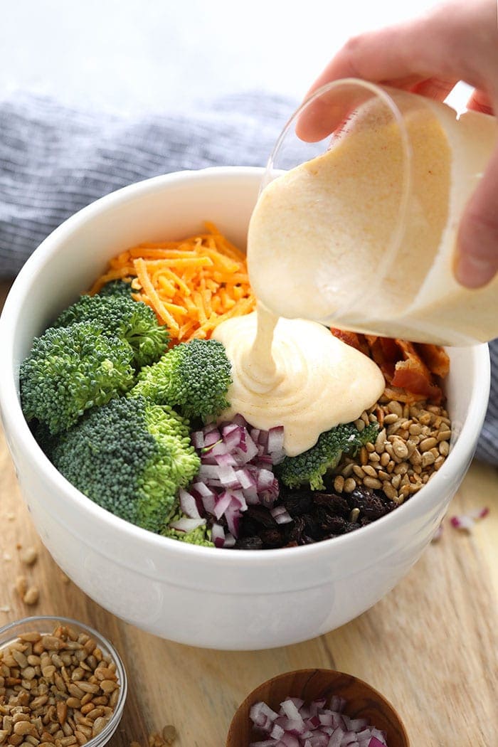 Pour healthy broccoli salad sauce over ingredients.
