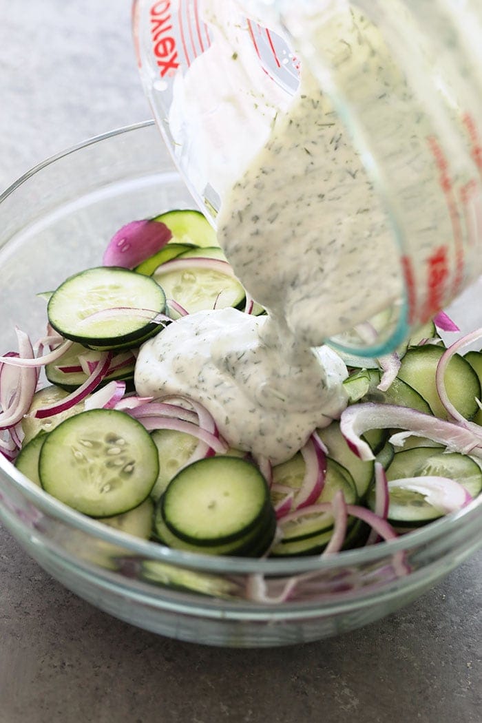 Pouring dressing on cucumber salad.