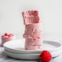 A stack of raspberry fat bombs on a white plate.