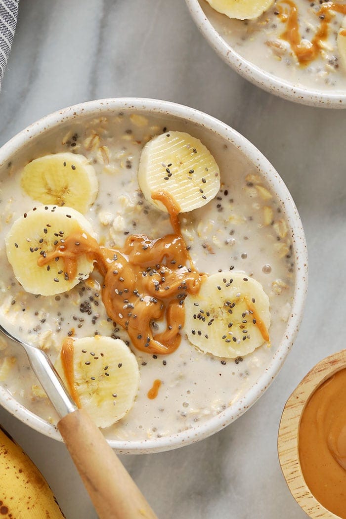 creamy banana overnight oats in a bowl topped with sliced bananas and chia seeds