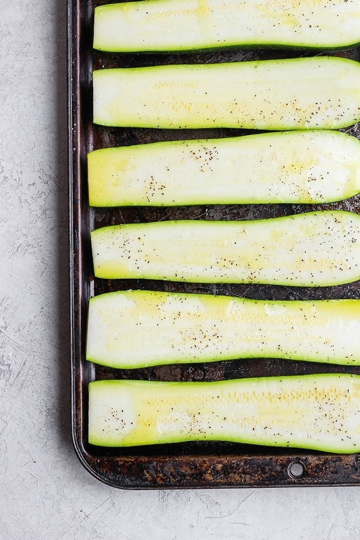 fresh zucchini on a baking sheet drizzled in oil.
