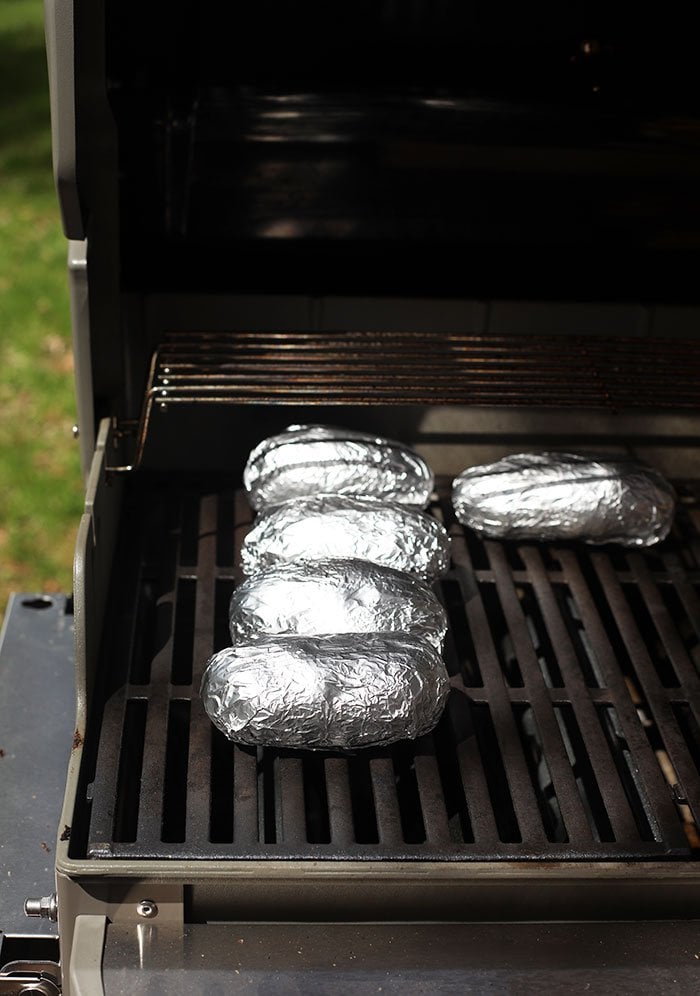 baked potatoes in foil on grill grates