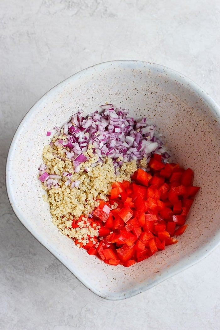 There Red onion, quinoa, and red pepper in a bowl