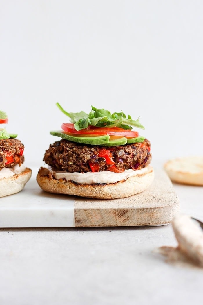 quinoa burgers on an english muffin with sauce, avocado, tomato, and arugula