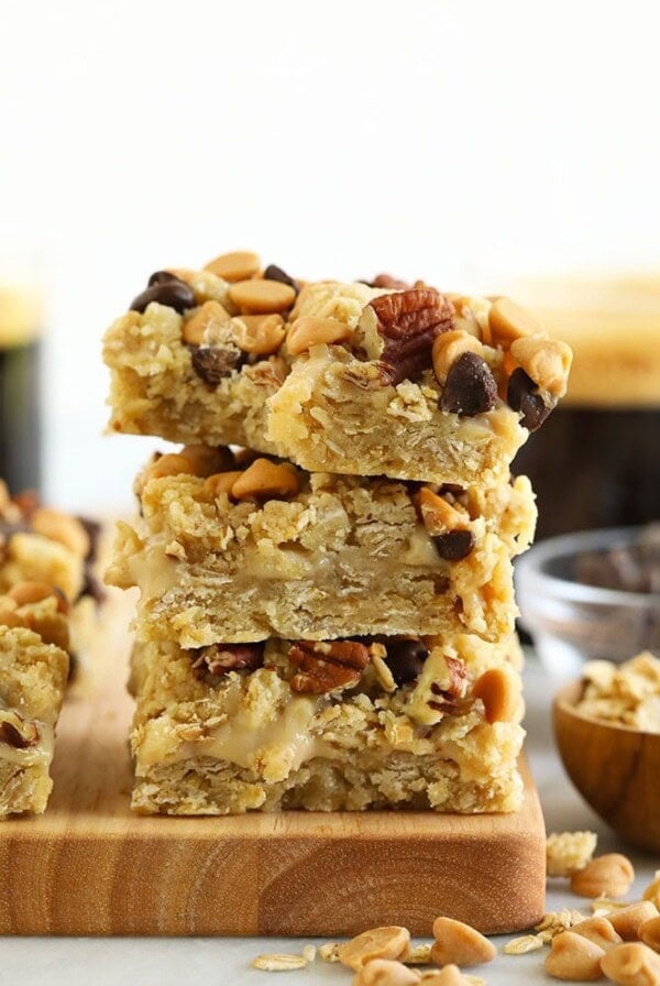 A stack of healthy peanut butter oatmeal bars, known as carmelita bars, displayed on a cutting board.