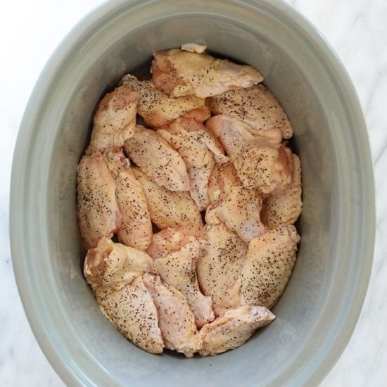 chicken in a crock pot on a marble countertop.