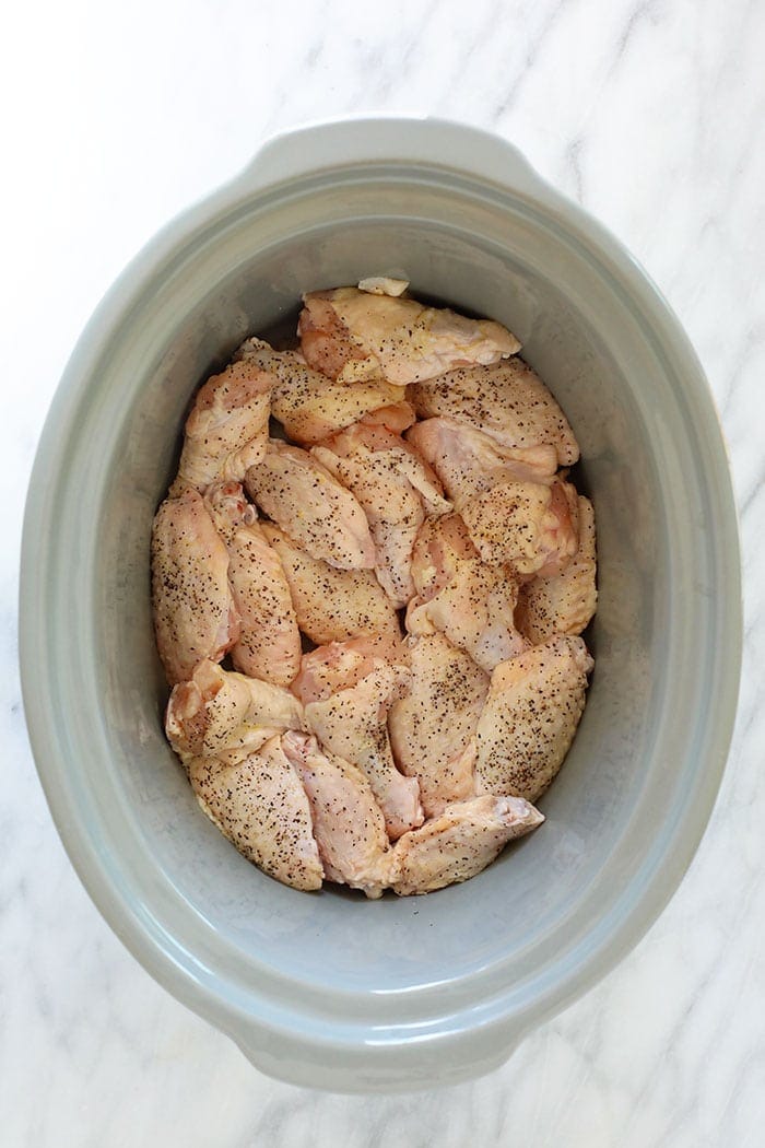 Love chicken wings but don't want to heat up your whole house? Make our amazing Crockpot Chicken Wings for your next appetizer or snack. Bonus: These Crockpot BBQ Chicken Wings aren't fried, so they're healthier! uncooked chicken wings in crockpot