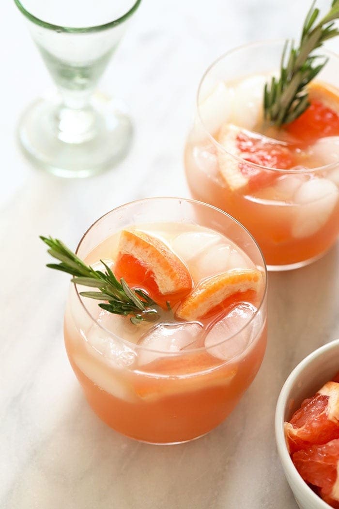 Two greyhound cocktails in a glass with a sprig of rosemary