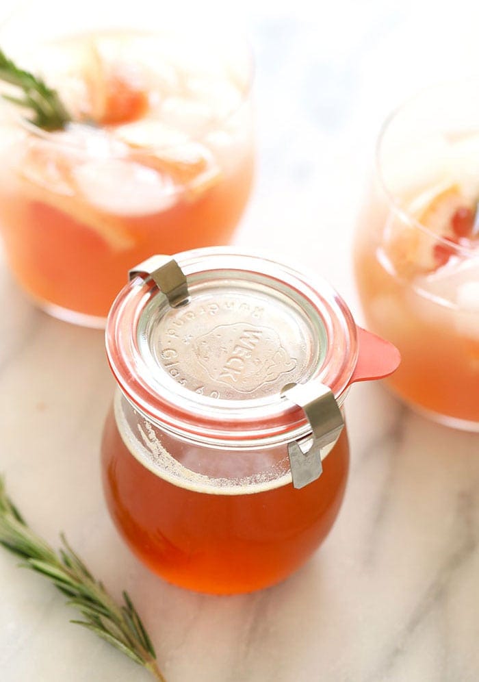 A jar of honey infused with a sprig of rosemary.