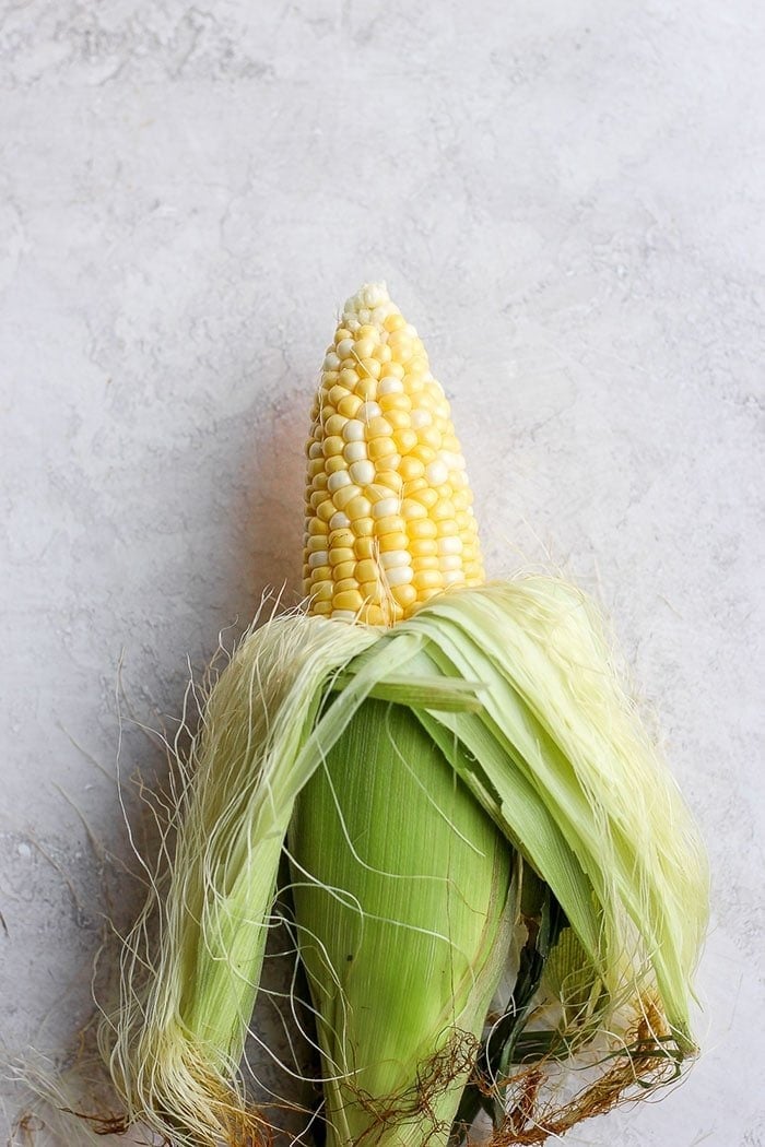 Half shucked corn on the cob.