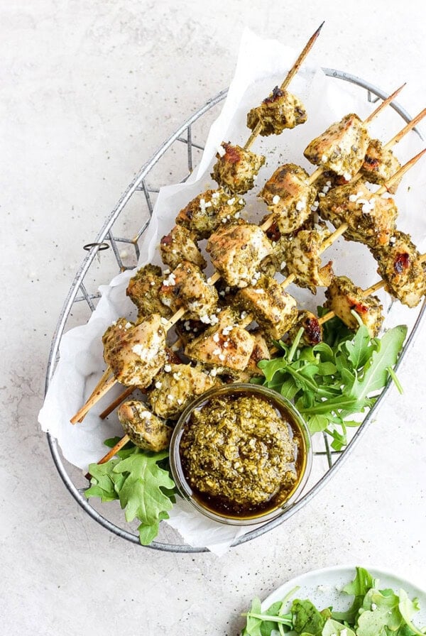 chicken skewers with pesto sauce on a plate.