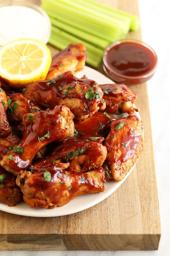 Love chicken wings but don't want to heat up your whole house? Make our amazing Crockpot Chicken Wings for your next appetizer or snack. Bonus: These Crockpot BBQ Chicken Wings aren't fried, so they're healthier! Plate of chicken wings with BBQ sauce