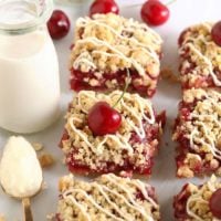 Cherry cobbler bars on a white plate with a glass of milk.
