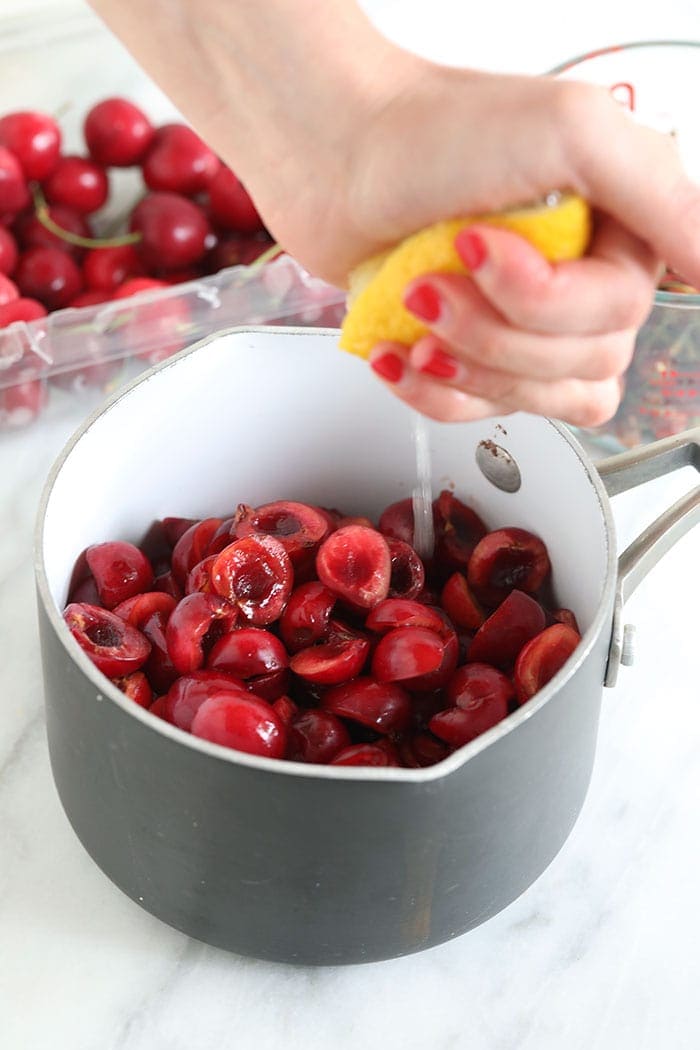 squeezing lemon juice into a saucepan of cherries