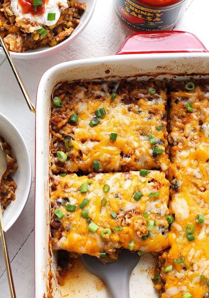 Mexican chicken casserole layered with sour cream and cheese in a baking dish.