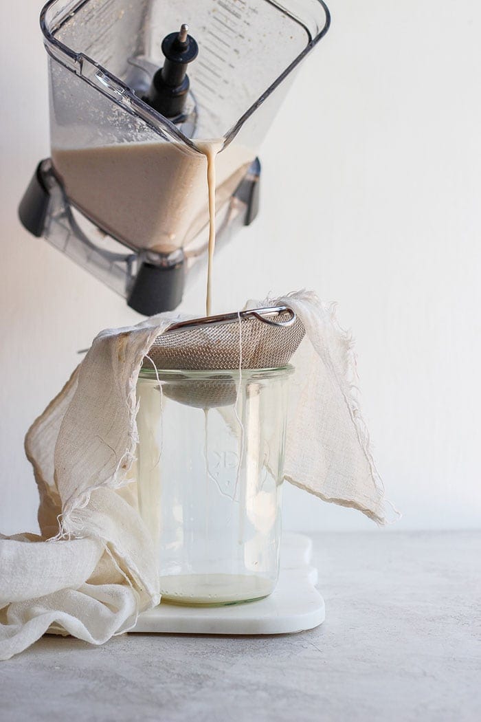 Pouring oat milk into a tea towel