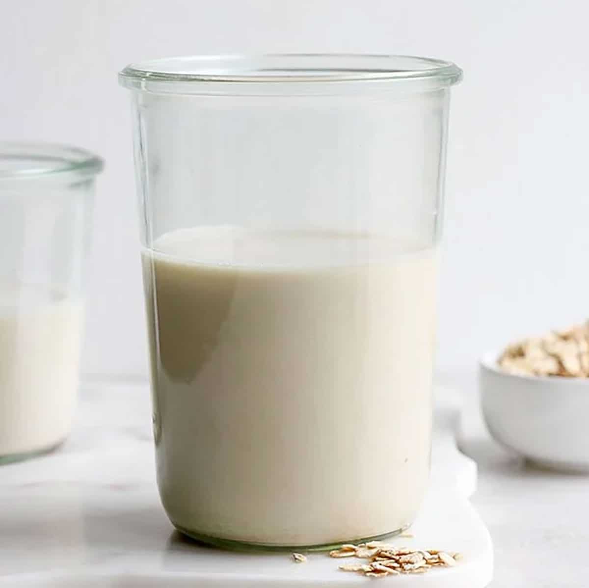 Free Photo  Milk carafe with bowl of almonds and bottle of milk high angle  view on a white wooden and piece of sack background