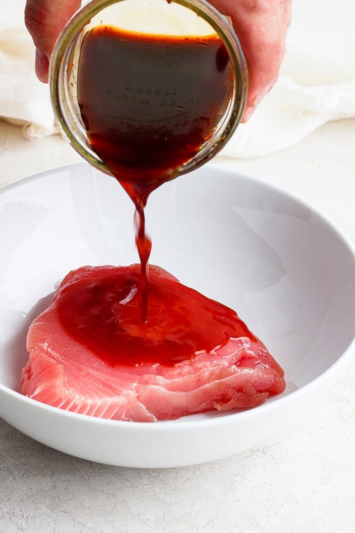 pouring marinade onto an ahi tuna steak