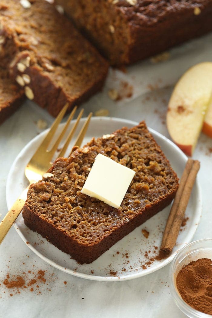 Slice of cinnamon apple bread on a plate with a pad of butter.