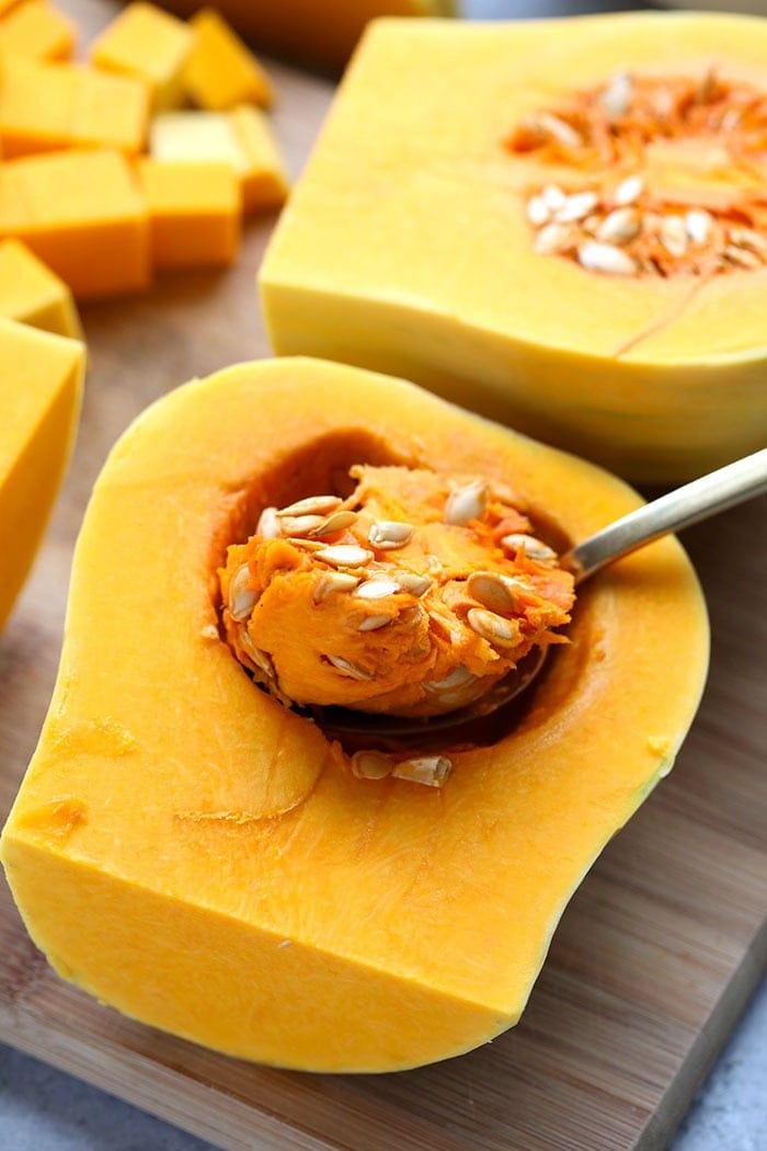 Butternut squash cut in half on a cutting board. 