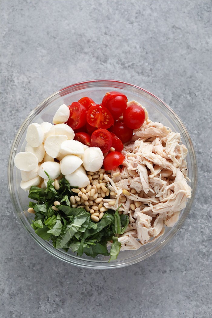 Ingredients for pesto chicken salad in a bowl.