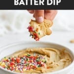 A person is dipping a cookie into a bowl of delicious Cake Batter Dip.